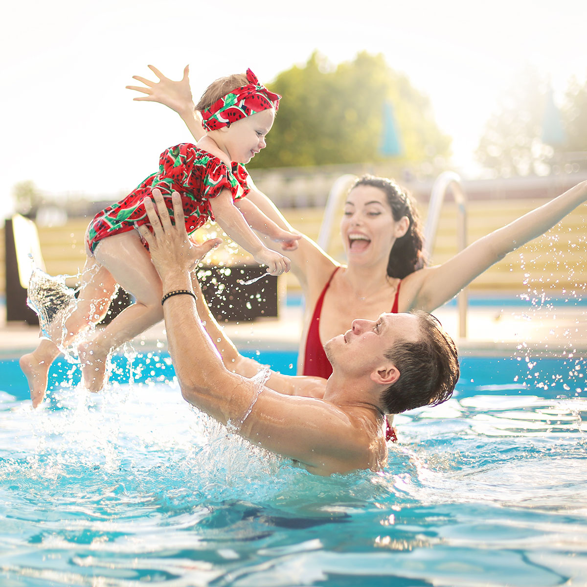 Happy Couple Playing With Baby In Pool