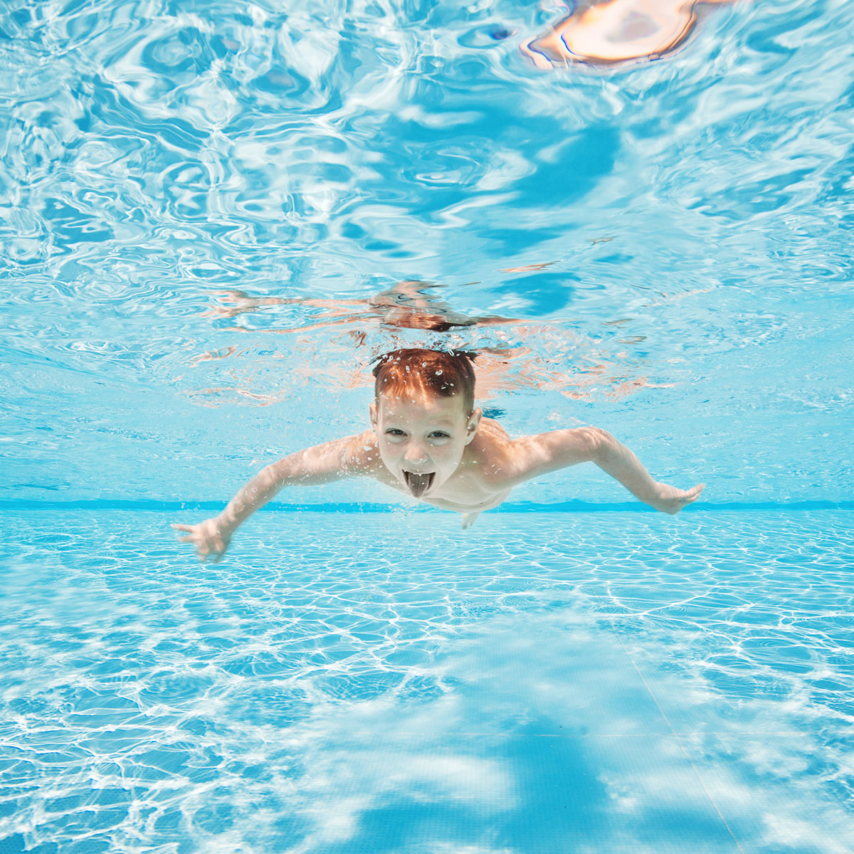 Little Boy Swimming Underwater In Pool